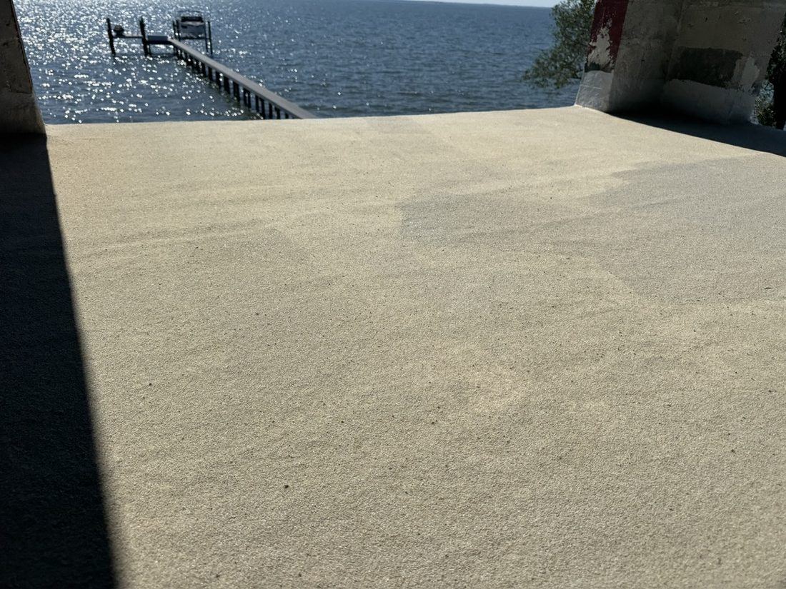 Textured waterproof deck coating on a bayfront terrace with dock beyond
