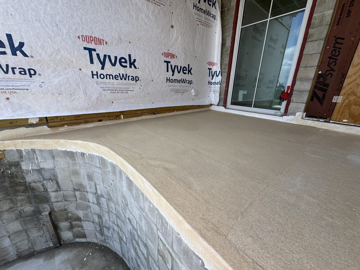 Waterproof coating on a curved concrete deck with block wall and house wrap behind