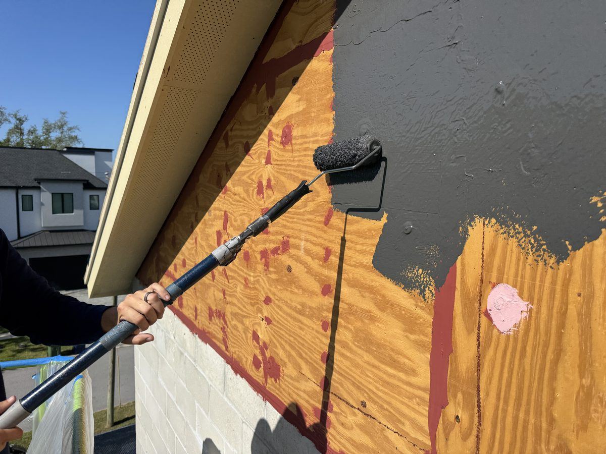 Applicator rolling fluid-applied air barrier over exterior wall sheathing
