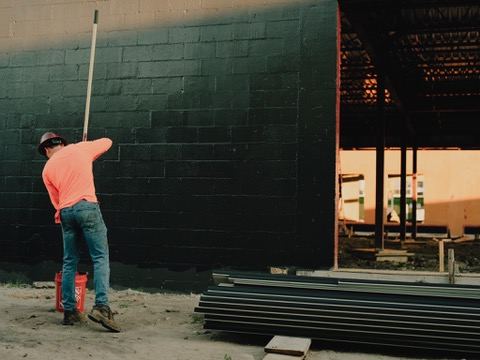 Crew member rolling fluid-applied barrier onto a CMU wall